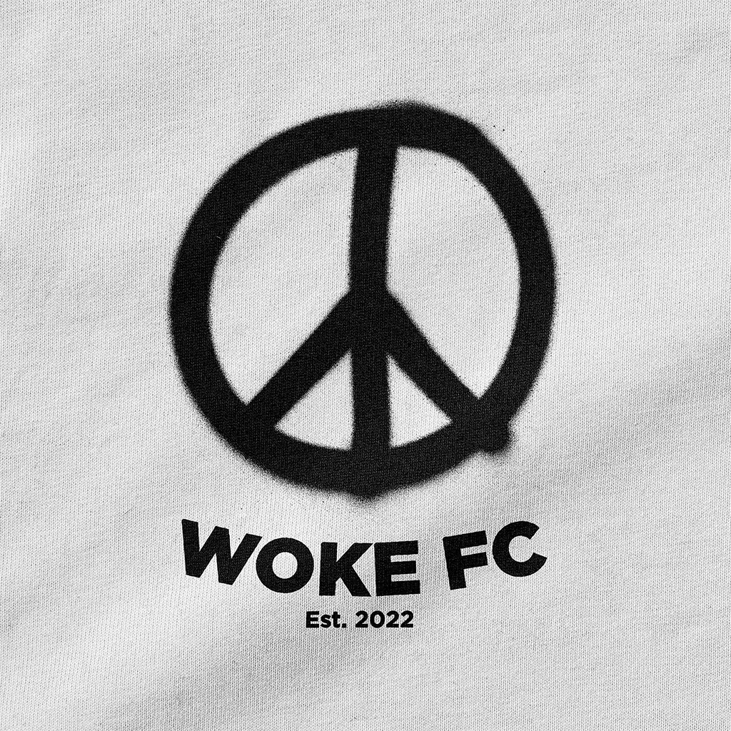 Peace symbol with 'WOKE FC Est. 2022' text on a light gray cotton background